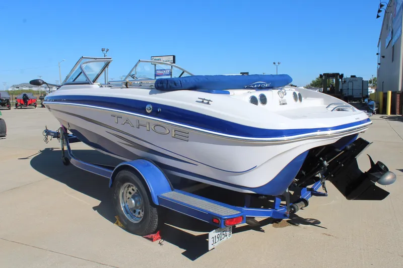 Slide: The Image of 2008 Tahoe Q5i SF boat on trailer, white and blue design, parked outdoors. - 6