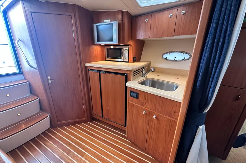 Slide: The Image of 2004 Tiara Yachts 3500 Open interior with kitchenette, wood cabinetry, and compact appliances. - 26