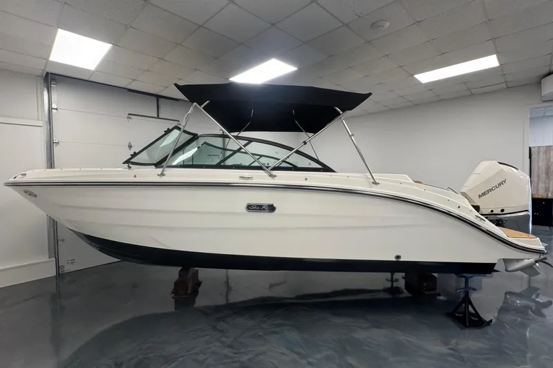 The Image of 2026 Sea Ray SDX 230 Outboard boat in showroom, featuring sleek design and Mercury engine. - 0