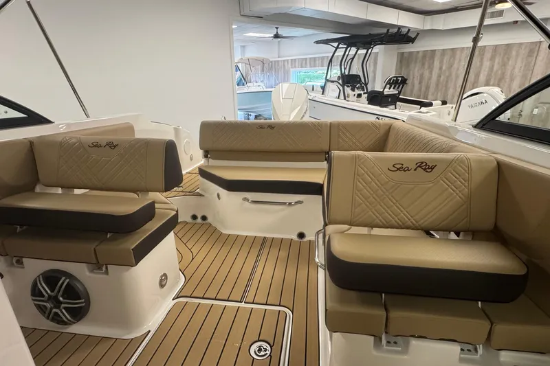 Slide: The Image of 2026 Sea Ray SDX 230 Outboard interior with tan seating and wood-style flooring. - 18