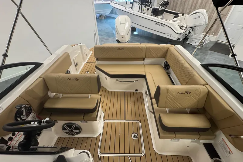 Slide: The Image of 2026 Sea Ray SDX 230 Outboard interior with tan seating and wood-style flooring. - 19
