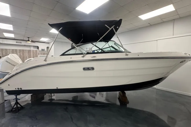 Slide: The Image of 2026 Sea Ray SDX 230 Outboard boat displayed indoors with black canopy. - 2
