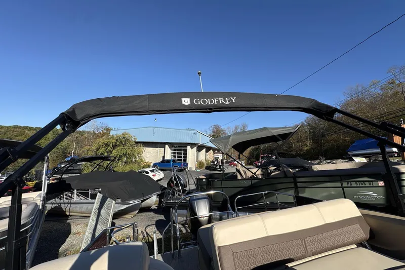 Slide: The Image of 2020 Godfrey Marine 22 boat with canopy, parked outdoors under clear blue sky. - 15