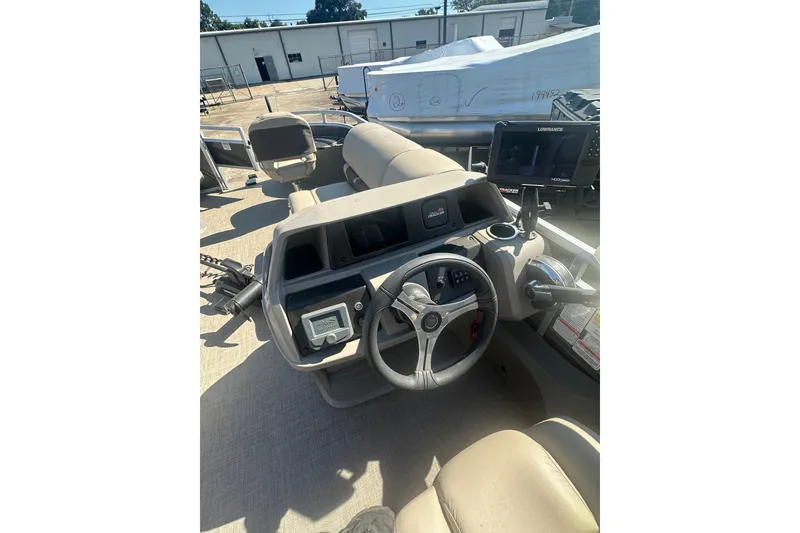 Slide: The Image of 2024 Sun Tracker Fishin' Barge 22 DLX helm with steering wheel and navigation display. - 12