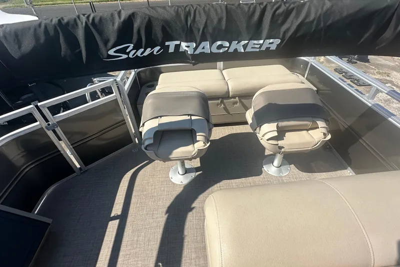Slide: The Image of 2024 Sun Tracker Fishin' Barge 22 DLX interior with seating and Sun Tracker logo. - 15