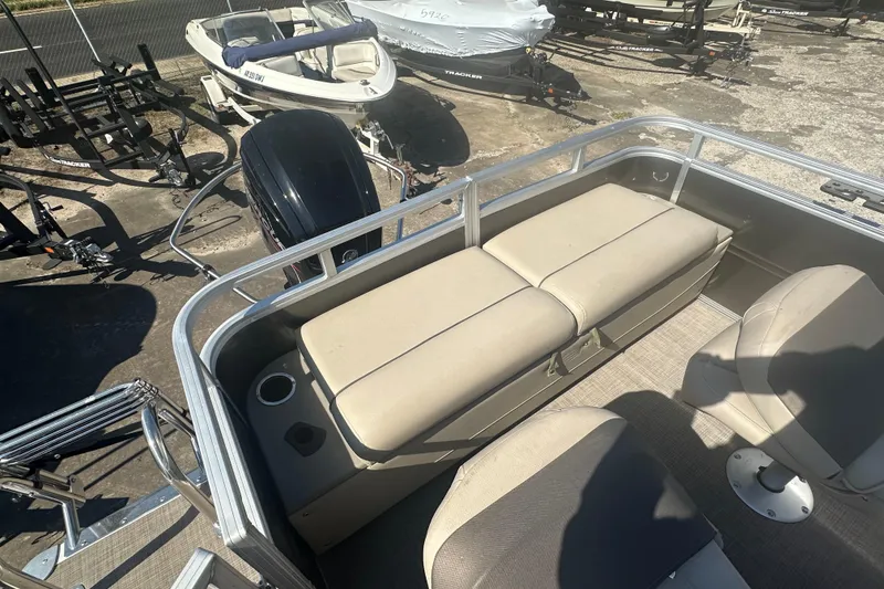 Slide: The Image of 2024 Sun Tracker Fishin' Barge 22 DLX interior with seating and motor, parked outdoors. - 17