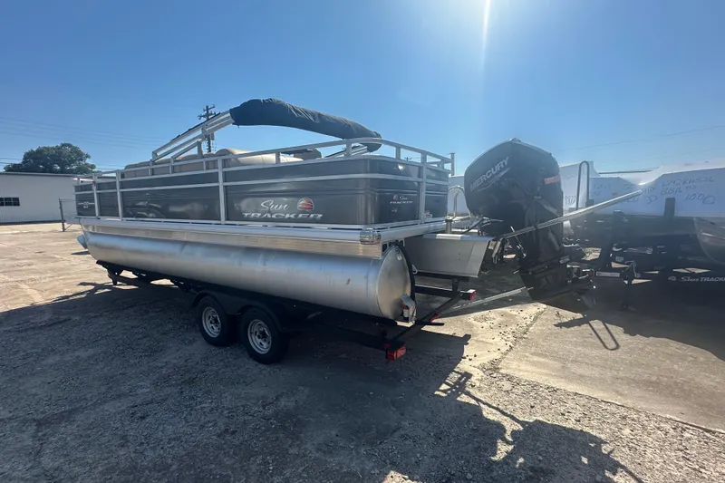 Slide: The Image of 2024 Sun Tracker Fishin' Barge 22 DLX pontoon boat on trailer, sunny day. - 3