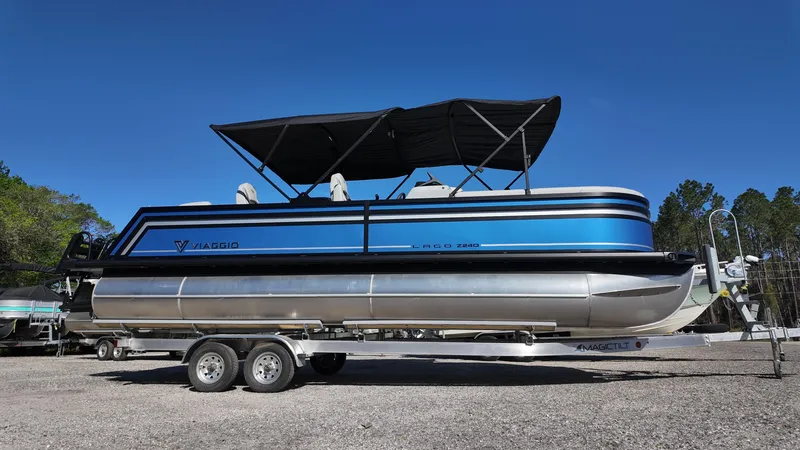 Slide: The Image of 2025 Viaggio Z24Q pontoon boat on trailer, blue and silver design, with canopy. - 2