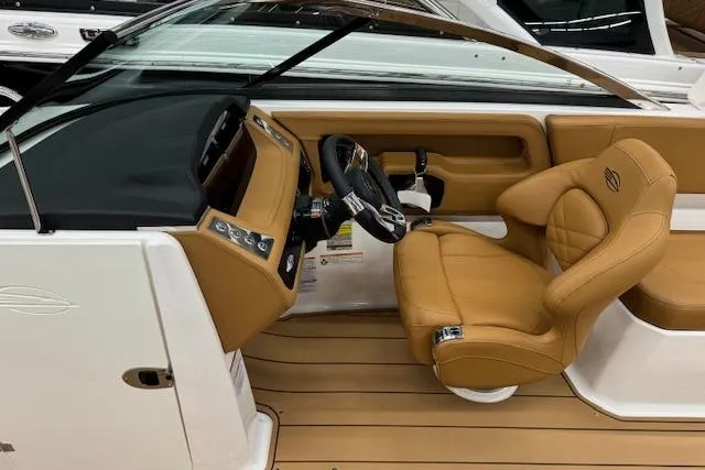 Slide: The Image of 2026 Chaparral 250 OSX boat interior with tan seating and sleek design in showroom. - 4
