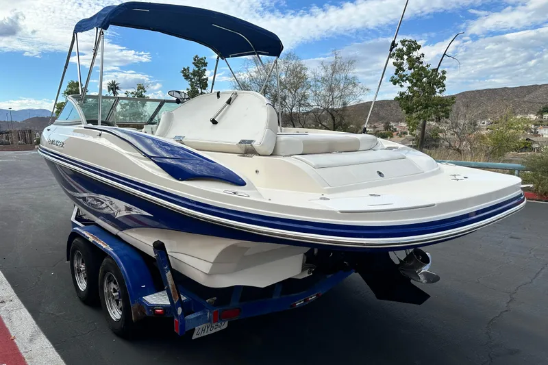 Slide: The Image of 2006 Rinker 226 Captiva Bowrider boat with blue canopy, parked on pavement. - 6