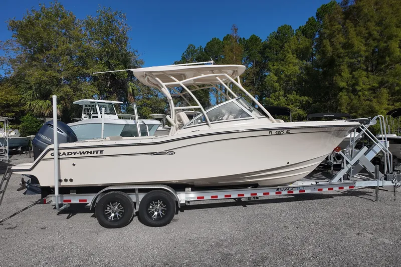 Slide: The Image of 2019 Grady-White Freedom 235 boat on trailer, parked outdoors, surrounded by trees. - 2