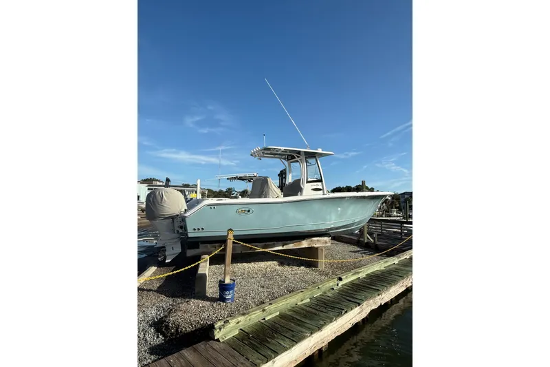 Slide: The Image of 2025 Sea Hunt Gamefish 25 boat on display at a marina under clear blue skies. - 2