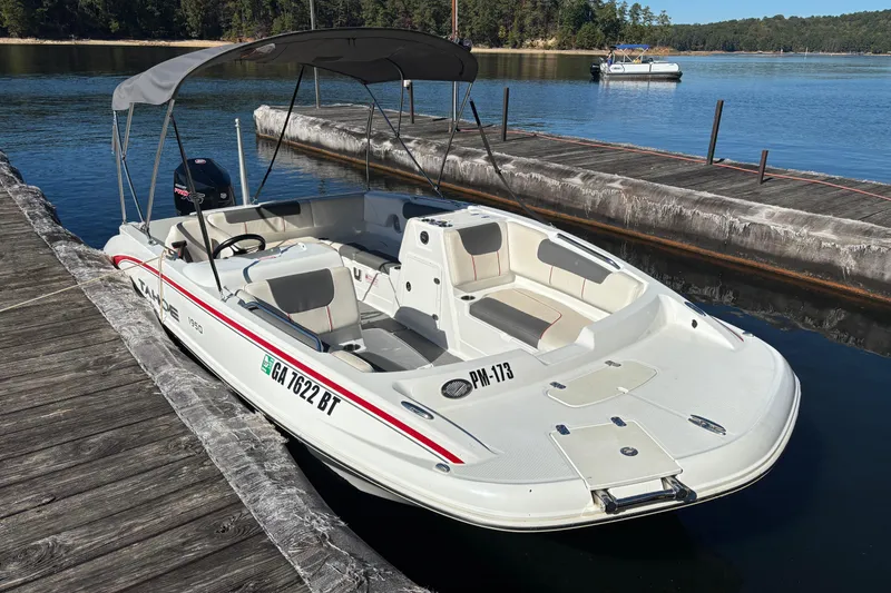 The Image of White 2021 Tahoe 1950 boat docked on a serene lake with canopy and seating. - 0