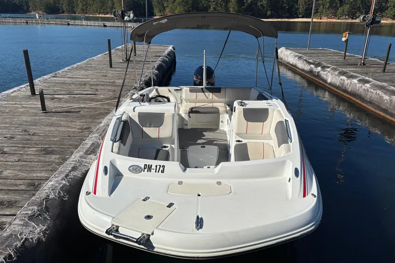 Slide: The Image of White 2021 Tahoe 1950 boat docked on a calm lake with wooden piers. - 2