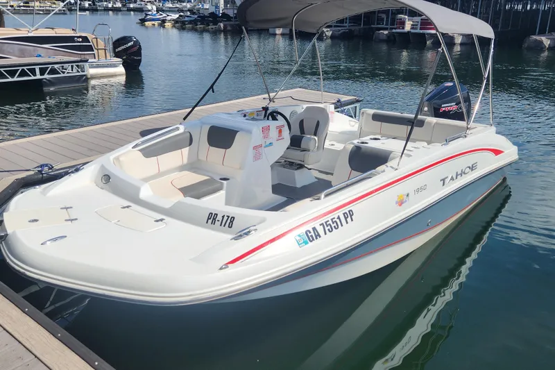 The Image of 2021 Tahoe 1950 boat docked at marina, featuring spacious seating and canopy. - 0