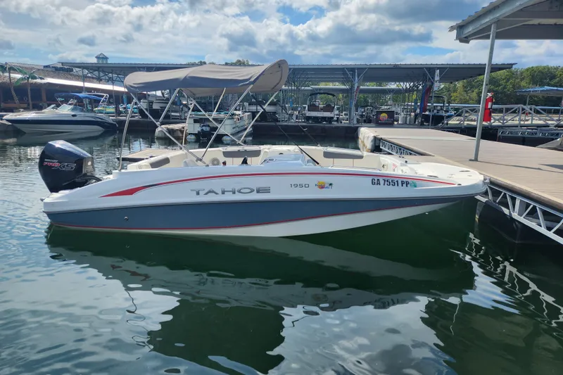 Slide: The Image of A 2021 Tahoe 1950 boat docked at a marina under a partly cloudy sky. - 3