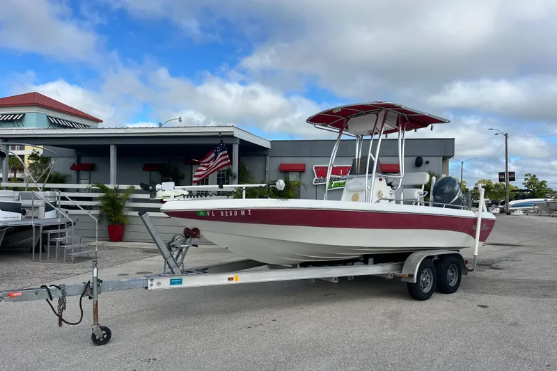 The Image of 2005 NauticStar 2200 Nautic Bay boat on trailer, parked outside a building under a cloudy sky. - 1