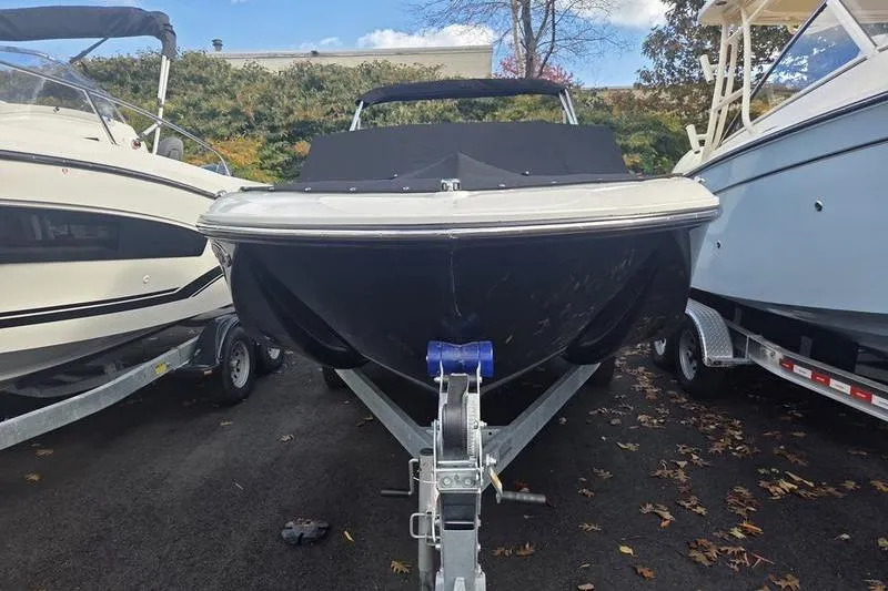 Slide: The Image of 2024 Bayliner M19 boat on trailer, parked between two other boats. - 6