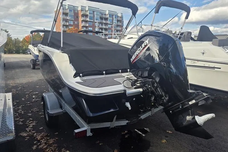 Slide: The Image of 2024 Bayliner M19 boat with Mercury outboard motor, covered and parked on a trailer. - 9