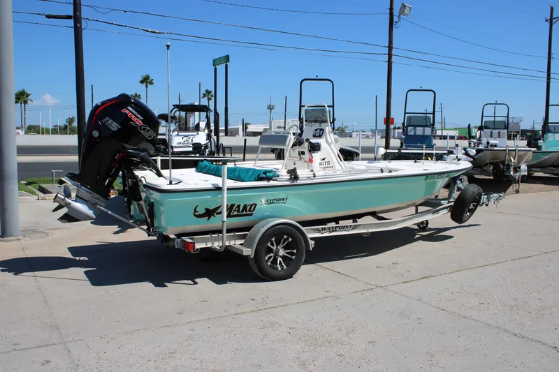 Slide: The Image of 2022 Mako 18 LTS boat on trailer, parked outdoors under clear blue sky. - 8