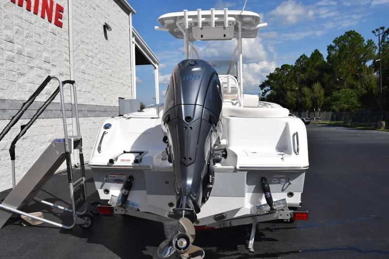 Slide: The Image of 2026 Sea Hunt Ultra 229 boat with outboard motor, parked near a building. - 5