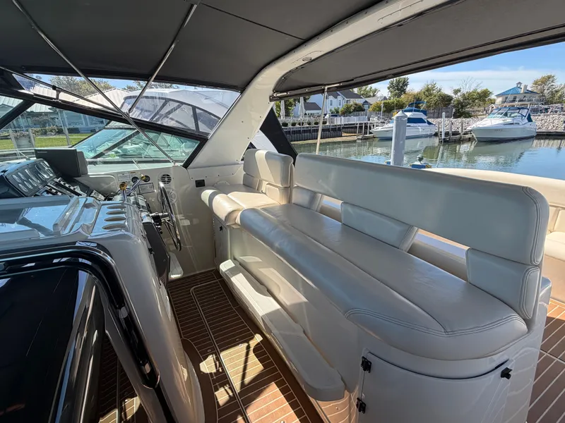 Slide: The Image of 1995 Tiara Yachts 3500 Express interior with white seating and helm, docked at marina. - 11