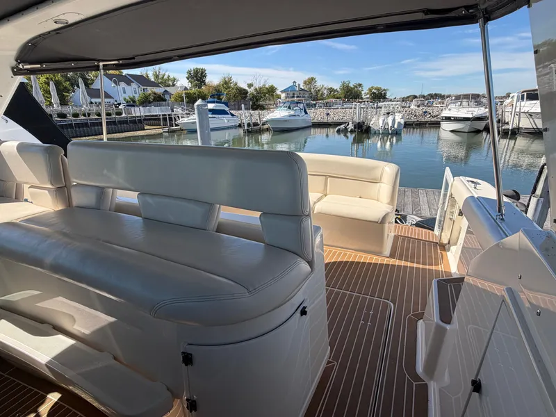 Slide: The Image of 1995 Tiara Yachts 3500 Express interior with white seating, docked at a marina. - 12