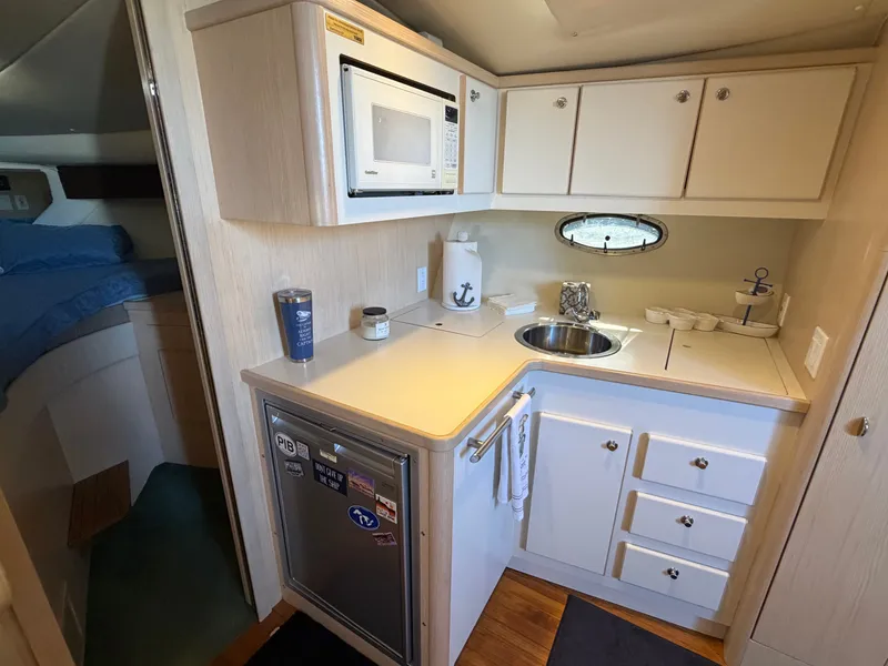 Slide: The Image of 1995 Tiara Yachts 3500 Express interior kitchen with microwave, sink, and compact fridge. - 18