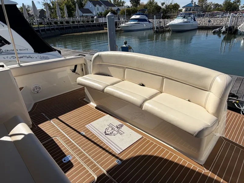 Slide: The Image of 1995 Tiara Yachts 3500 Express interior with beige seating and wooden deck at marina. - 6