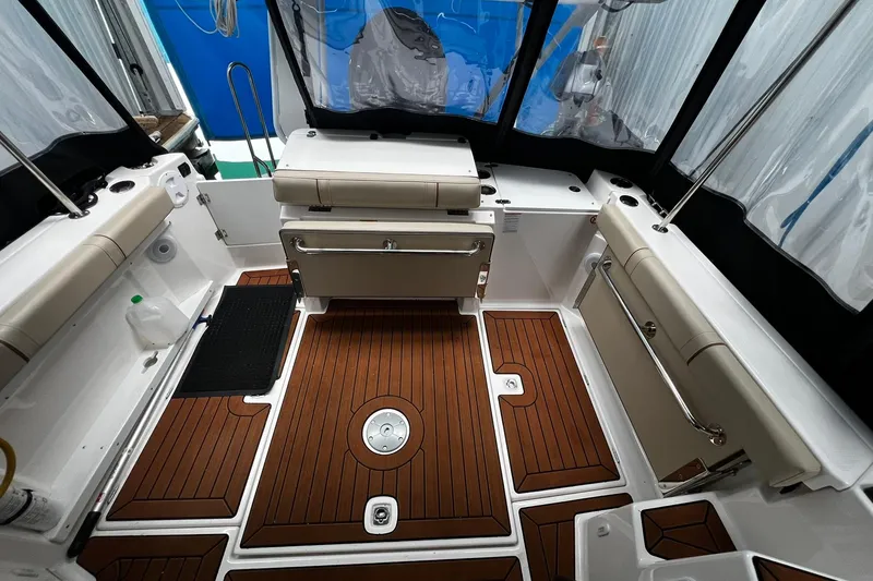 Slide: The Image of 2025 Ranger Tugs R-27 boat interior with teak flooring and cushioned seating. - 14