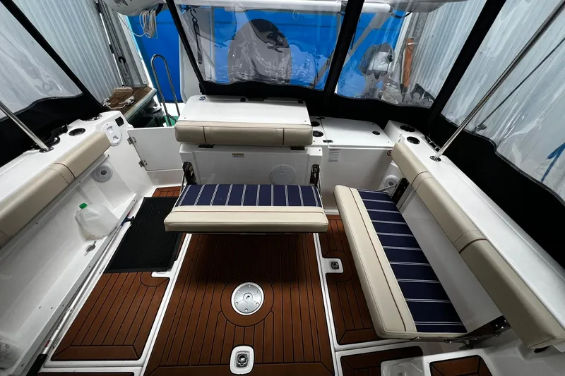Slide: The Image of 2025 Ranger Tugs R-27 boat interior with cushioned seating and wood-style flooring. - 15