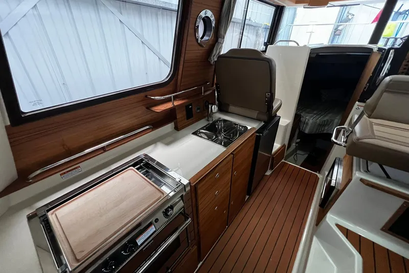 Slide: The Image of 2025 Ranger Tugs R-27 interior with modern kitchen and wood accents. - 18