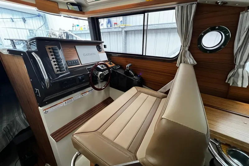 Slide: The Image of 2025 Ranger Tugs R-27 helm with Garmin navigation, wood accents, and comfortable seating. - 21