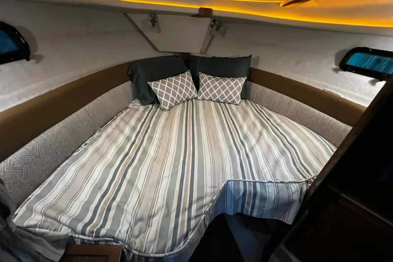 Slide: The Image of Cozy cabin interior of 2025 Ranger Tugs R-27 with striped bedding and ambient lighting. - 22