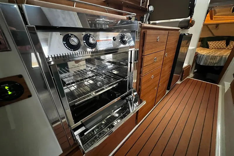 Slide: The Image of 2025 Ranger Tugs R-27 interior kitchen with modern oven and wooden cabinetry. - 29