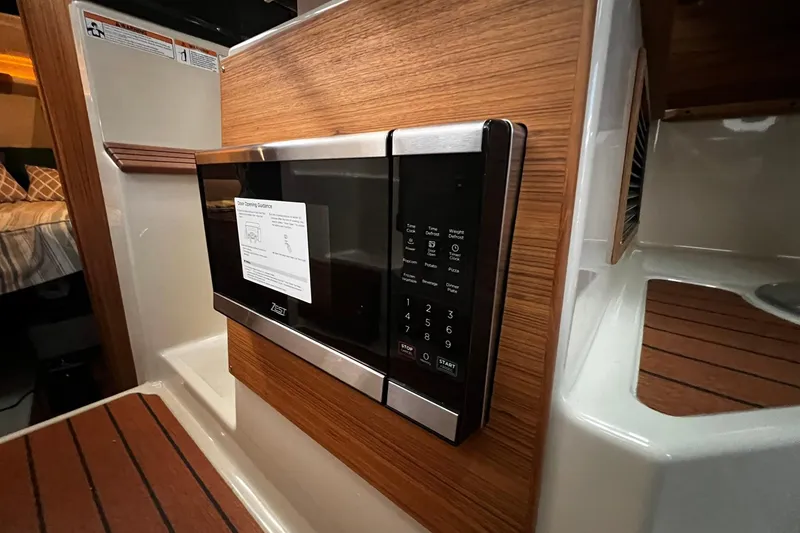 Slide: The Image of 2025 Ranger Tugs R-27 interior with modern microwave and wood paneling. - 30