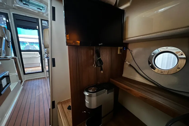 Slide: The Image of 2025 Ranger Tugs R-27 interior with TV, porthole, and coffee maker. - 31