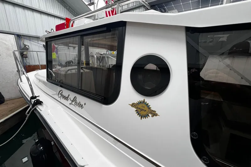 Slide: The Image of 2025 Ranger Tugs R-27 boat docked indoors, featuring sleek design and "Good Livin'" text. - 9