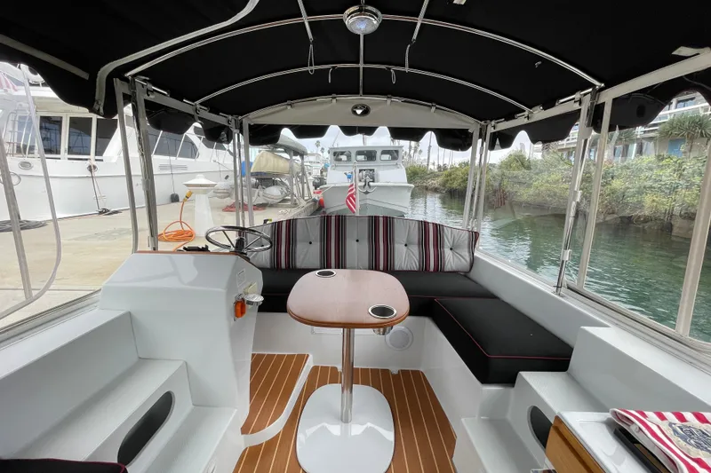 Slide: The Image of 2020 Duffy Snug Harbor 18 boat interior with seating, table, and steering wheel. - 10