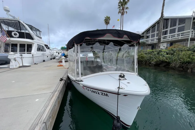 Slide: The Image of 2020 Duffy Snug Harbor 18 electric boat docked at marina, overcast sky. - 4