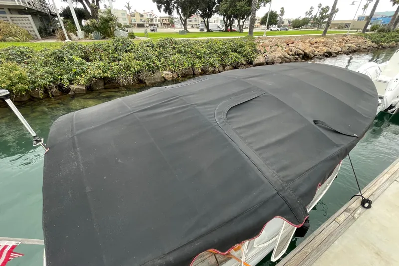 Slide: The Image of 2020 Duffy Snug Harbor 18 boat with black cover docked by a lush shoreline. - 6