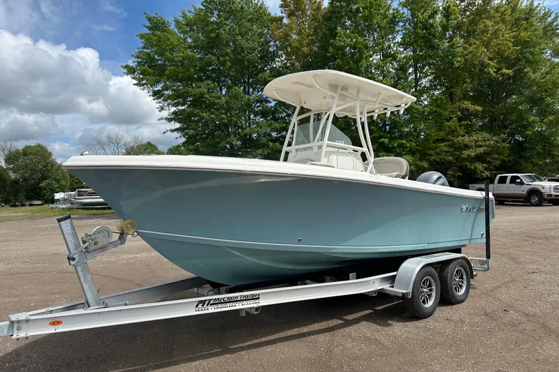 The Image of 2023 Sailfish 220 CC boat on trailer, parked outdoors with trees in background. - 0