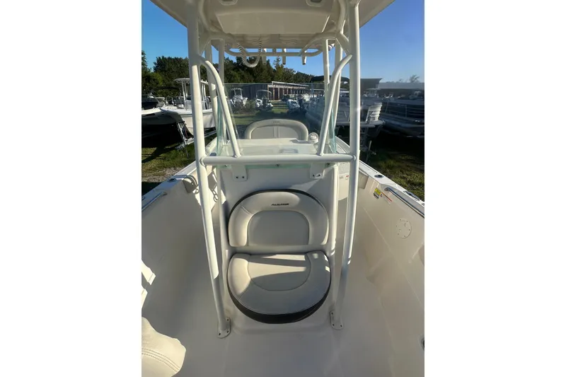 Slide: The Image of 2023 Sailfish 220 CC boat interior with seating and console, parked outdoors. - 10