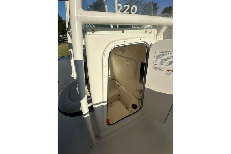 Slide: The Image of 2023 Sailfish 220 CC boat storage compartment with open door, showcasing interior space. - 12