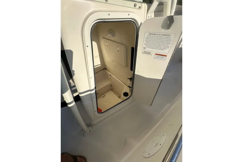 Slide: The Image of 2023 Sailfish 220 CC boat interior storage compartment with open door. - 13