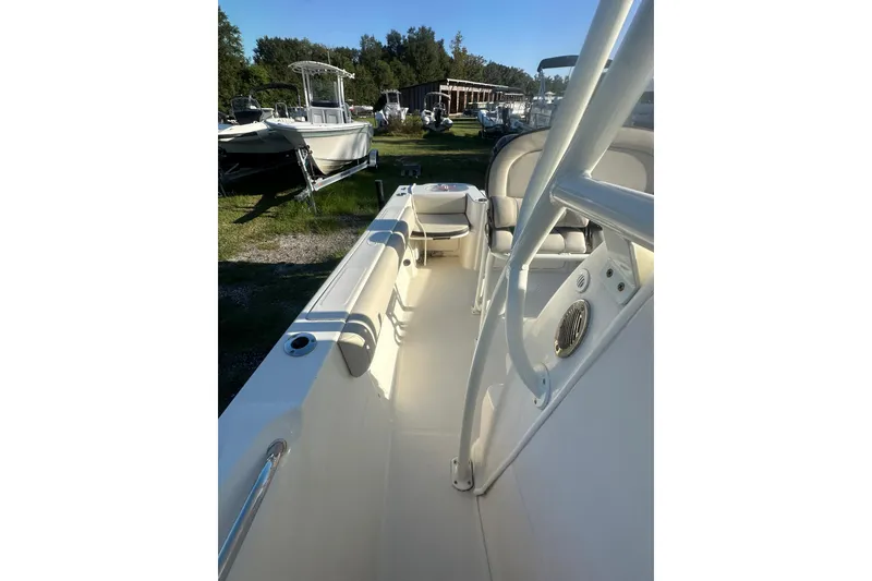Slide: The Image of 2023 Sailfish 220 CC boat interior with seating and console, parked outdoors. - 17