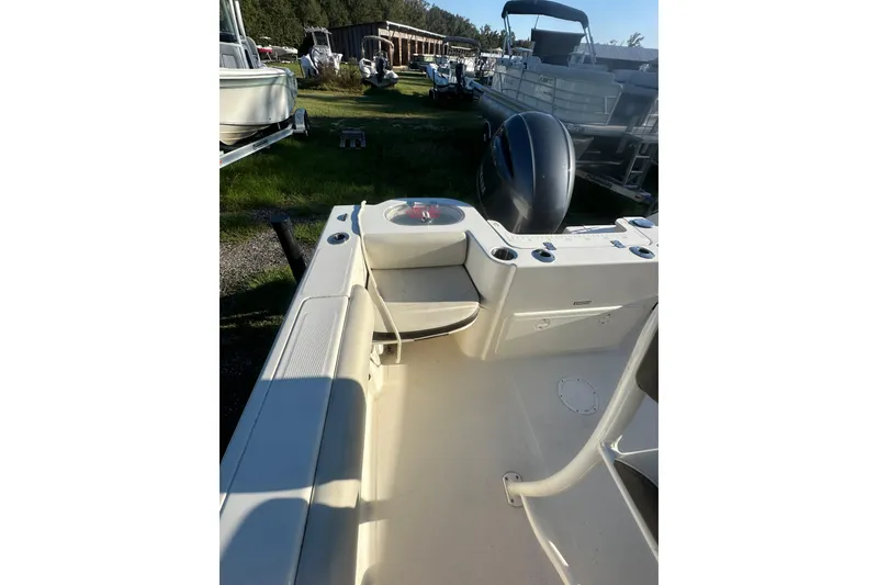 Slide: The Image of 2023 Sailfish 220 CC boat interior with seating and motor, parked outdoors. - 19