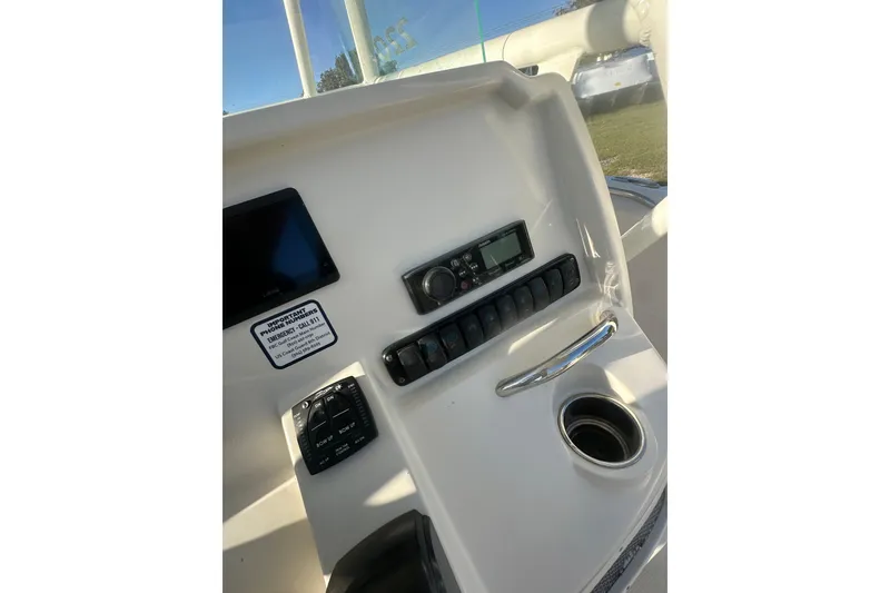 Slide: The Image of 2023 Sailfish 220 CC boat dashboard with control panel and cup holder. - 23