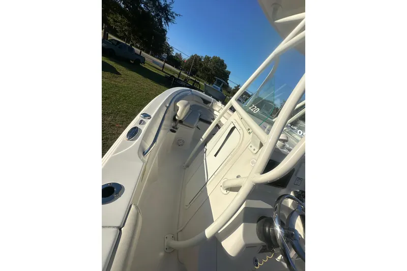 Slide: The Image of 2023 Sailfish 220 CC boat interior with steering wheel and seating, under clear blue sky. - 32