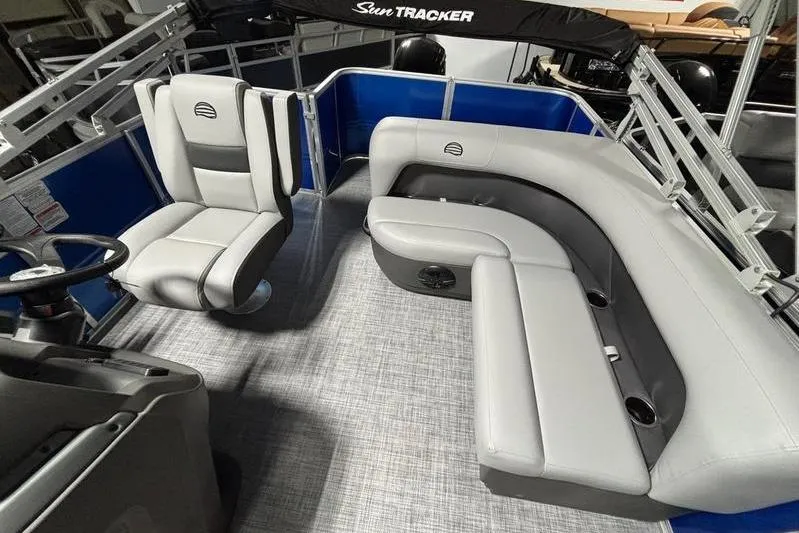 Slide: The Image of 2026 Sun Tracker Party Barge 18 DLX interior with gray seating and steering console. - 2